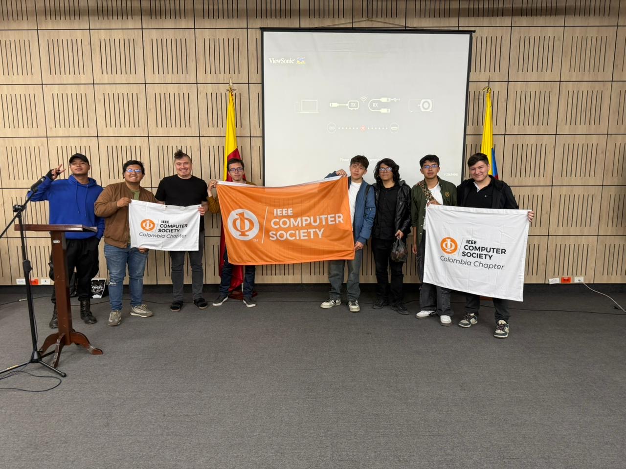 Group photo with IEEE Computer Society Colombia Chapter flags at Universidad Distrital Francisco José de Caldas, Bogotá